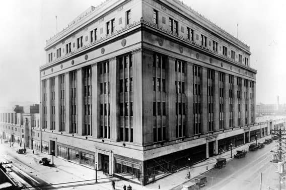 Black and white photo of a classical-style building with vintage cars on the street